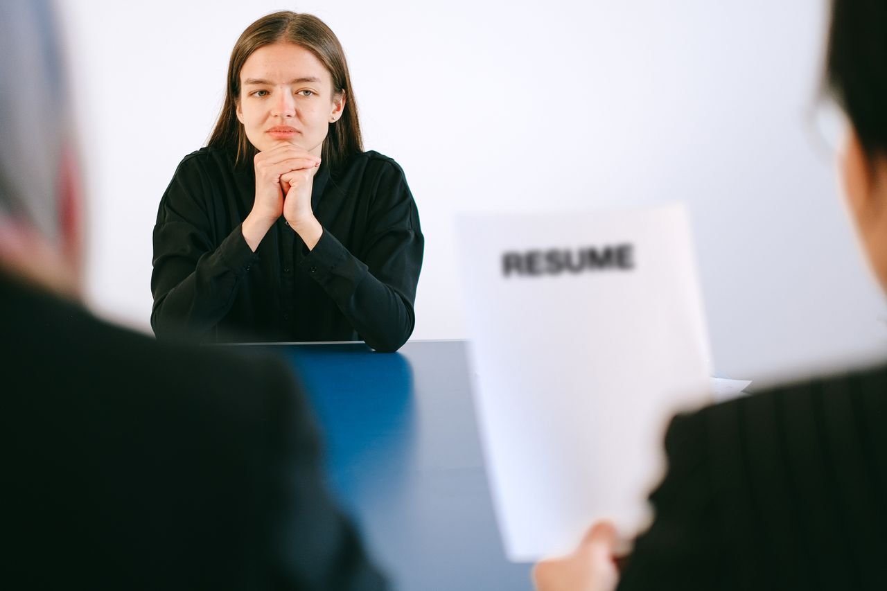 Mastering the First Impression: Your intriguing post title goes here A woman in a job interview facing two employers with a focus on her resume.