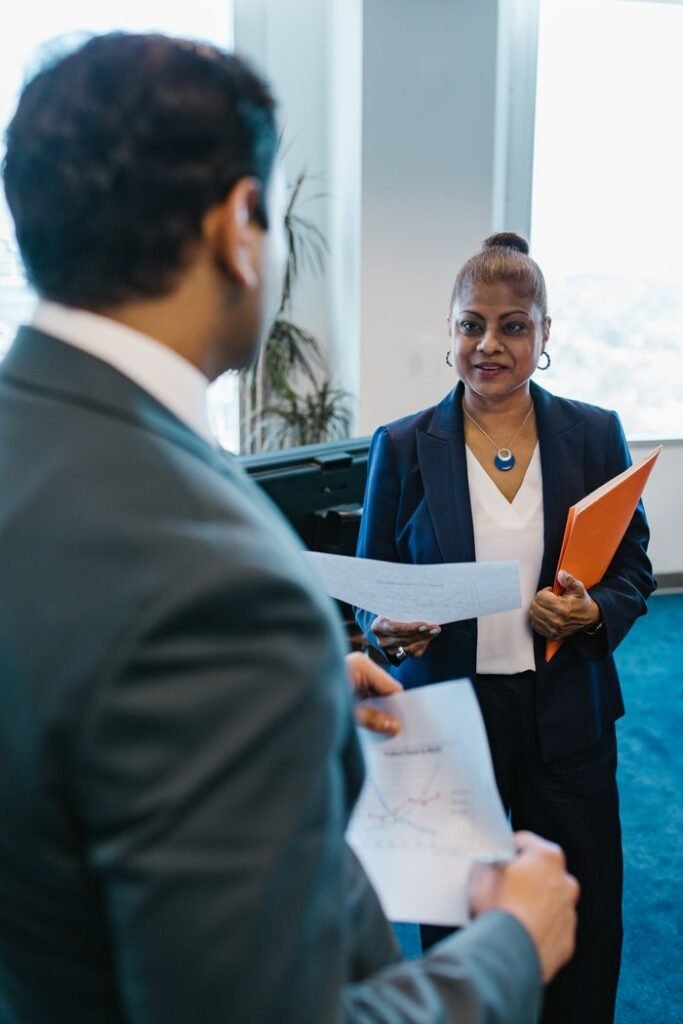 Two professionals discussing business documents in a modern office environment.